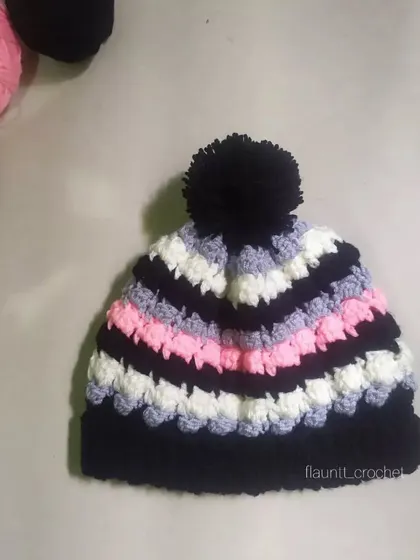 The Dolci Beanie is all about texture and color. I combined black, white, grey, and pink yarn to create this fun, striped beanie with a large black pom-pom on top.