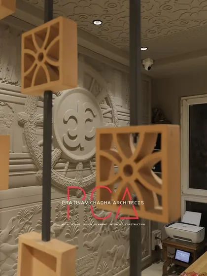 A detailed view showing the interplay between the terracotta partition, the carved wall panel, and the reception desk at the Jubinav Chadha studio.