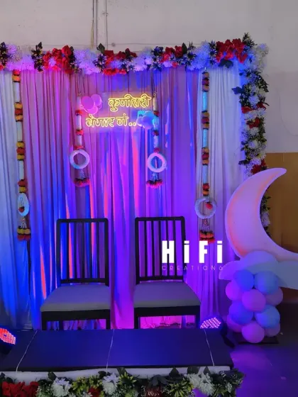 A simple and elegant seating arrangement for a traditional baby shower ceremony at home, complete with a custom neon sign in Marathi.