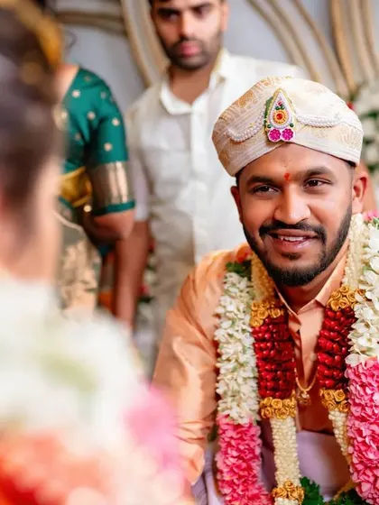 An over the shoulder shot of the groom looking at his bride with a smile during the muhurtham. This perspective creates a personal and intimate feel.