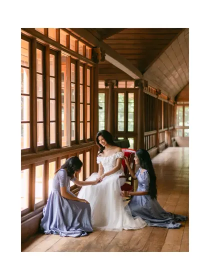 A bride in her white gown, sharing a tender moment with her bridesmaids. The scene, set in a beautiful wood-paneled hall, feels like a painting come to life.
