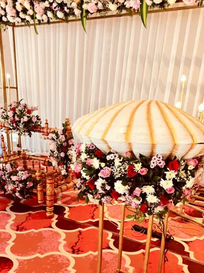 A side view of the naming ceremony stage, showing the cradle and the decorative floral stands against the elegant backdrop.