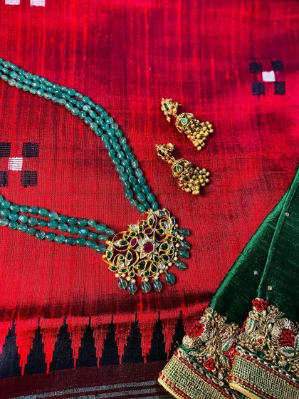 A masterpiece jewellery set designed by me, featuring a stunning green beaded necklace with a traditional pendant. It pairs perfectly with this rich red dupion silk saree.