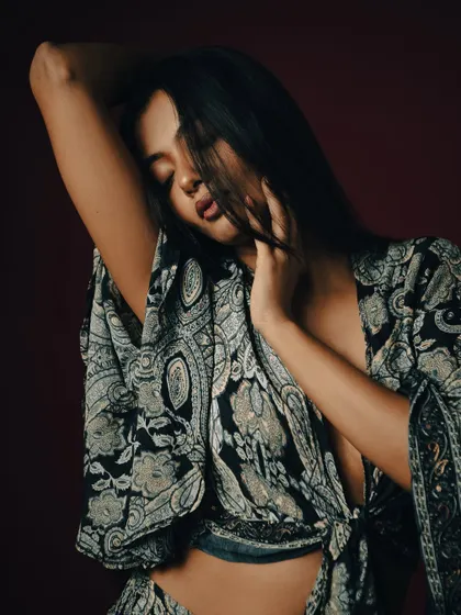 An intimate and expressive pose, with the model's hair partially obscuring her face.