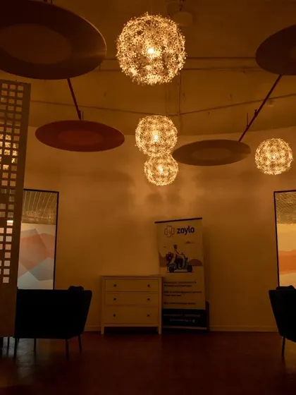 A lounge in a common cafe area, featuring warm, ambient lighting from spherical pendant lights and decorative screens for privacy.