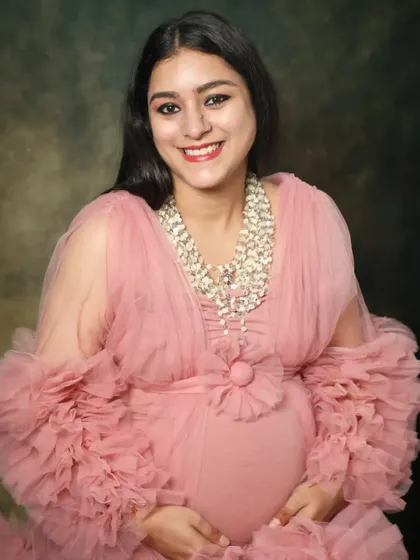 A beautiful close-up of a smiling mom-to-be in a frilly pink gown. Her happy expression and the soft texture of the dress create a joyful and feminine portrait.