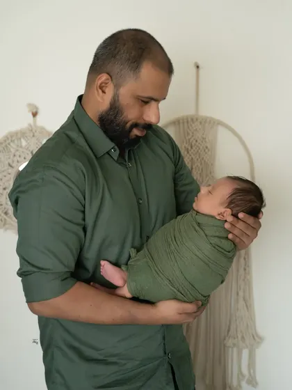 A father looking down at his newborn, swaddled in a lovely olive green wrap. This is a quiet, strong portrait that captures the beginning of a lifelong bond.