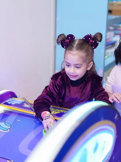 A girl enjoys a competitive game of air hockey, one of the many arcade games available.