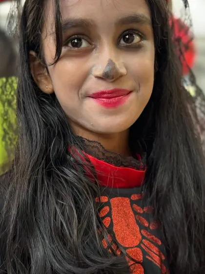 A sweet smile from a girl in her Halloween costume, complete with skeleton makeup and a lace veil. She's ready for a day of fun.