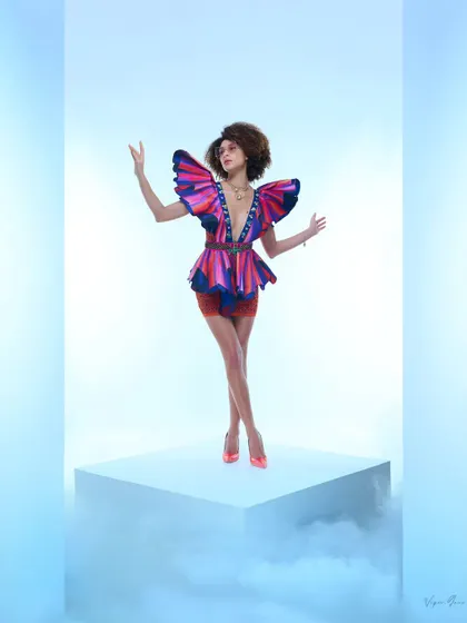 An artistic shot for a designer collection, focusing on structural and colourful garments. The model's pose and the butterfly-like shoulders of the top create a powerful, high-fashion statement.