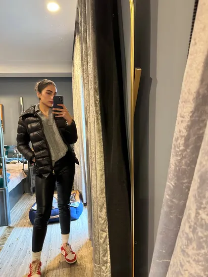 An edgy winter look with a puffer jacket, grey sweater, and faux leather pants.