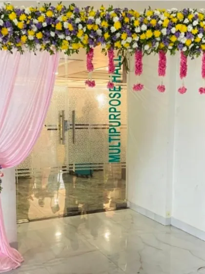 The entrance to a multipurpose hall decorated with a vibrant floral header, hanging tassels, and pink drapery.