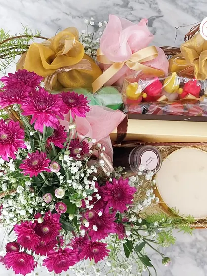 This traditional hamper combines a basket of fresh flowers with beautifully wrapped dry fruits, sweets, and a large scented candle.