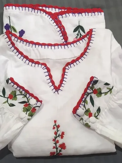 We added a custom red crochet lace trim to the neckline and cuffs of this beautiful embroidered white top. It's a great way to add a pop of color and a handmade detail.