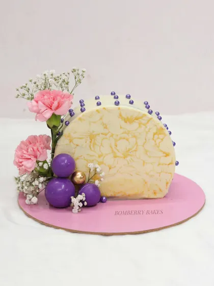 A modern half-arch cake with a marble-effect chocolate sail and floral decorations. This unique shape and design is a key project in my advanced cake structure and decoration class.