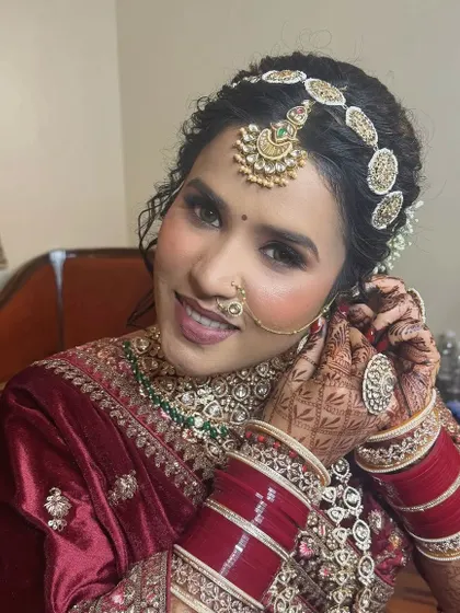 A candid moment of the bride getting ready. The traditional chooda and nath are essential elements of her stunning North Indian bridal look.