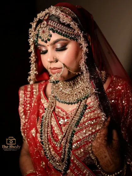 A classic, elegant portrait of the bride looking down. This pose highlights her beautiful jewelry and the details of her bridal lehenga.