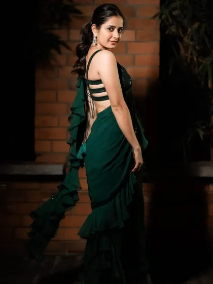 This emerald green saree gown is my modern take on a classic silhouette, designed for actress Ashika Ranganath. It combines the ease of a gown with the elegance of a saree, featuring cascading ruffles and a stylish strappy back for a contemporary cocktail look.