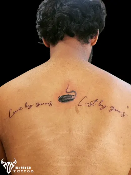 This back tattoo uses fine-line script and a detailed bullet design to cover up a previous, smaller tattoo. The new elements are strategically placed to integrate and hide the old ink.