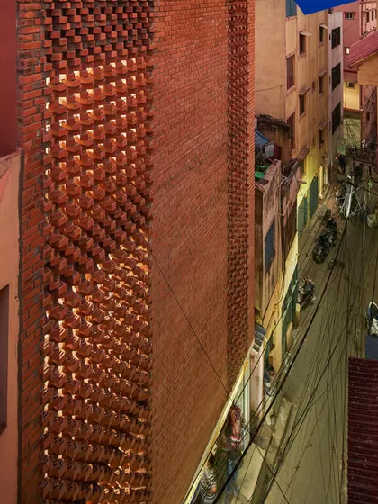 The 'Brick Weave House' situated in a dense urban lane. The brick facade provides a strong visual identity while maintaining privacy from the close-set neighboring buildings.
