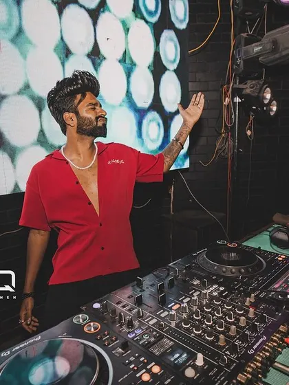 Posing by the decks at Freq Club, with the club's logo and a vibrant LED background.