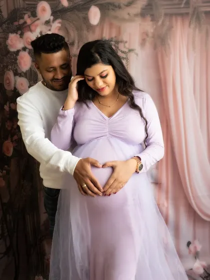 A sweet pose with the couple's hands forming a heart. The soft lavender of the gown and the floral background create a dreamy atmosphere.