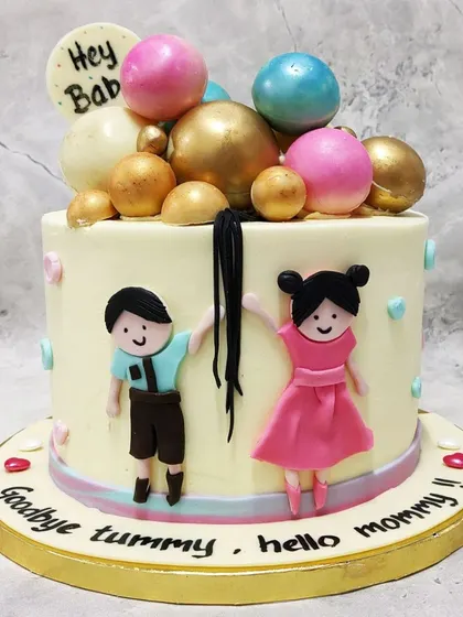 We celebrate the parents-to-be with this fun and charming "Goodbye Tummy, Hello Mommy" baby shower cake. Featuring cute figures of the couple and a cascade of colorful spheres, this cake is a joyful way to welcome the next chapter.