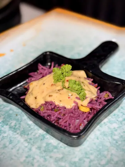 An individual serving of the Purple Rice, topped with a creamy paprika sauce and fresh parsley. It's a dish that's as beautiful as it is delicious.