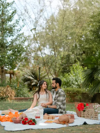 A beautiful wide shot of the picnic setup, showing the couple enjoying a quiet moment in a lush garden setting.