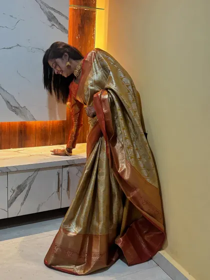 Sonu Srinivas Gowda in a gorgeous golden-beige silk saree with a red border, perfect for a housewarming ceremony.