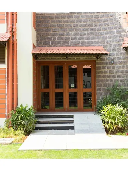A close-up of an entrance, where the warmth of the wooden door and tiled awning contrasts beautifully with the cool texture of the stone wall.