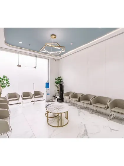 The waiting area is designed for patient comfort, with ample seating arranged to offer a sense of personal space. The clean white marble floors, high ceilings, and abundant natural light create a calm and spacious atmosphere.