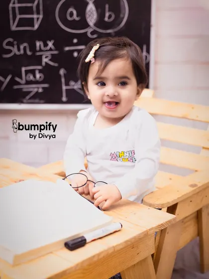 A big, happy smile from our little scholar. The details of the 'back to school' theme, like the tiny glasses, make this first birthday shoot so memorable.