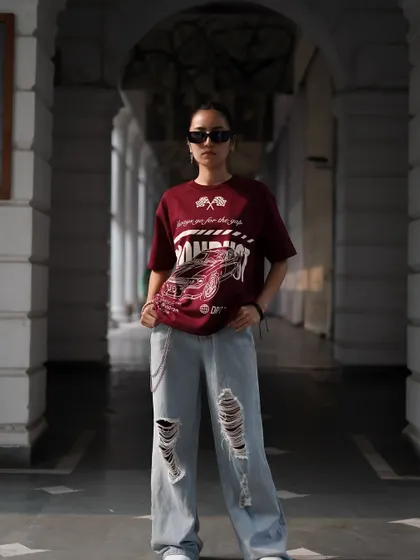 A direct, full-body shot that puts the focus squarely on the t-shirt and the model's confident stance. The depth of the hallway creates leading lines that draw the eye to the product.