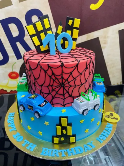 A 5kg two-tiered Spider-Man cake with a web-covered top tier and a city-themed bottom tier.