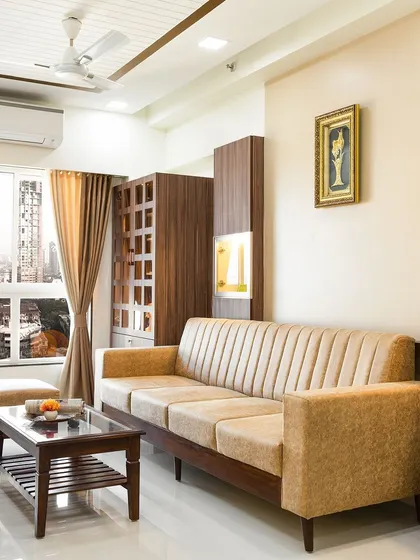 A warm and inviting living room with a beige sofa, dark wood furniture, and a large window offering a beautiful city view.