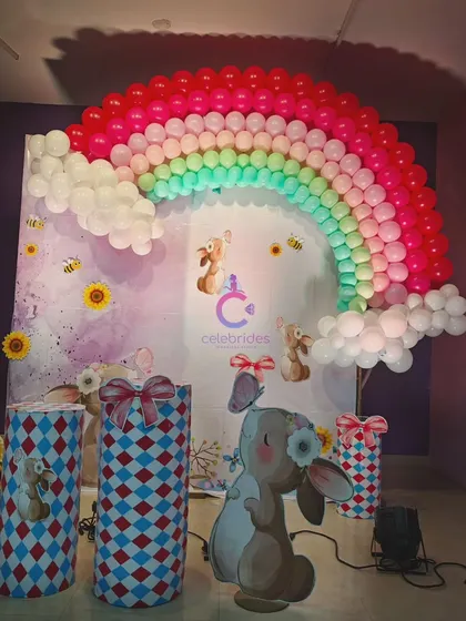 A sweet bunny-themed birthday decoration. The pastel rainbow balloon arch and cute bunny cutouts create an adorable and whimsical atmosphere.