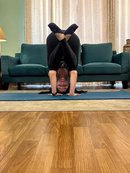 Headstand with legs folded in lotus, balanced in front of my sofa.