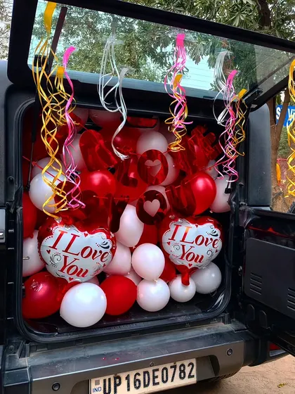 If you want a surprise that's different, I can do a car boot decoration. I fill the car boot with balloons and ribbons, like this red and white 'I Love You' theme, so you can reveal the surprise anywhere you like.