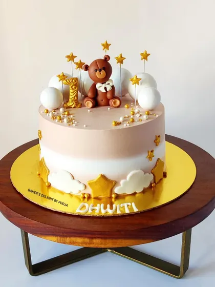 The full view of the beige and white teddy bear cake, a sophisticated and sweet design for a baby's first milestone.