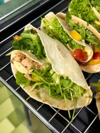 A close-up of a perfectly folded and baked chicken taco wrap, showcasing the fresh and healthy fillings.