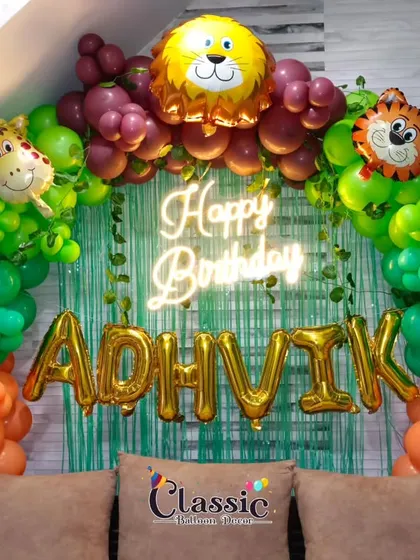 A vibrant jungle theme decoration for a home party, featuring an arch with animal foil balloons, a neon sign, and a greenery backdrop.