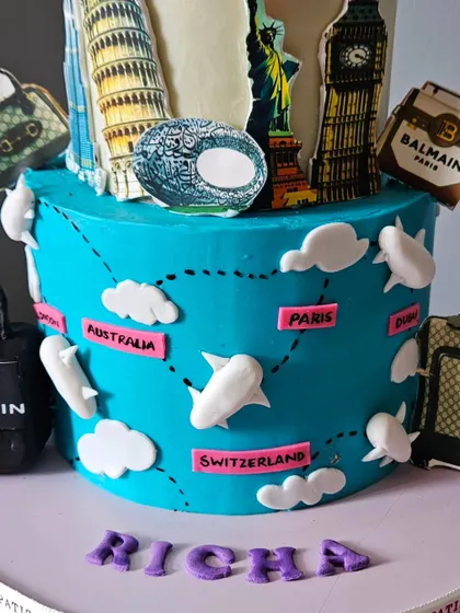 A detailed view of the travel-themed cake, showing the world map with flight paths connecting different destinations like Paris and Dubai.