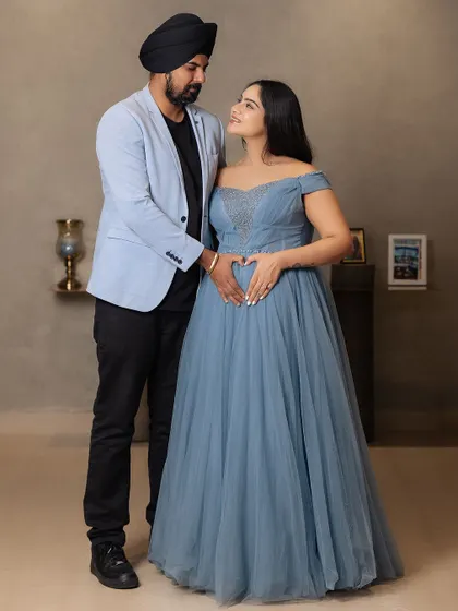 A classic portrait of the expecting couple. The mother-to-be makes a heart shape with her hands on her belly, a sweet and timeless gesture of love for their coming baby.