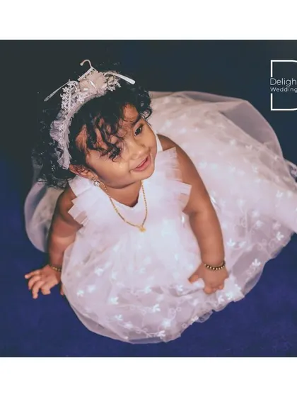 An angelic top-down shot of the birthday girl in her white party dress and tiara, looking up with a sweet expression.