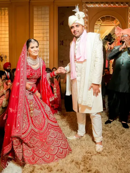 A candid moment as the couple makes their entrance at the wedding. The groom leads his bride by the hand, and her happy smile is beautiful to see.