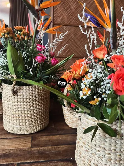 A close-up of the beautiful floral arrangements in woven baskets, featuring a mix of tropical and classic flowers in shades of orange and pink.