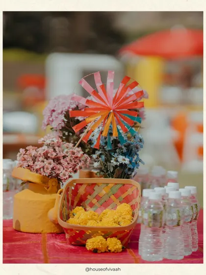 A close-up of a table at the Kite Carnival, with a colorful pinwheel, marigolds in a woven basket, and other small details that contribute to the festive, mela-like atmosphere.