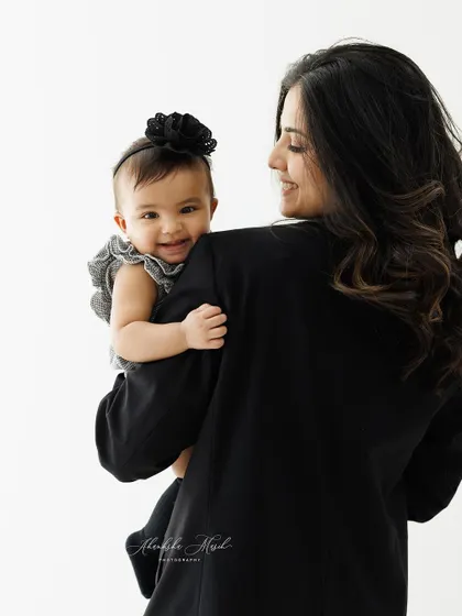A modern and chic mother-daughter portrait. The mother's black blazer contrasts beautifully with her baby's happy smile, creating a stylish and timeless image.