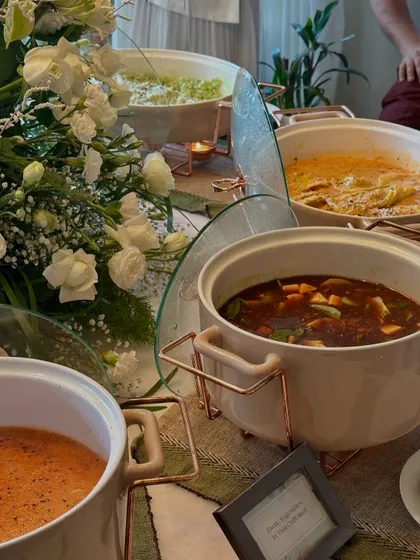 A wide shot of our buffet setup, featuring a mix of Italian and Asian main courses in elegant serving dishes, surrounded by white floral arrangements.